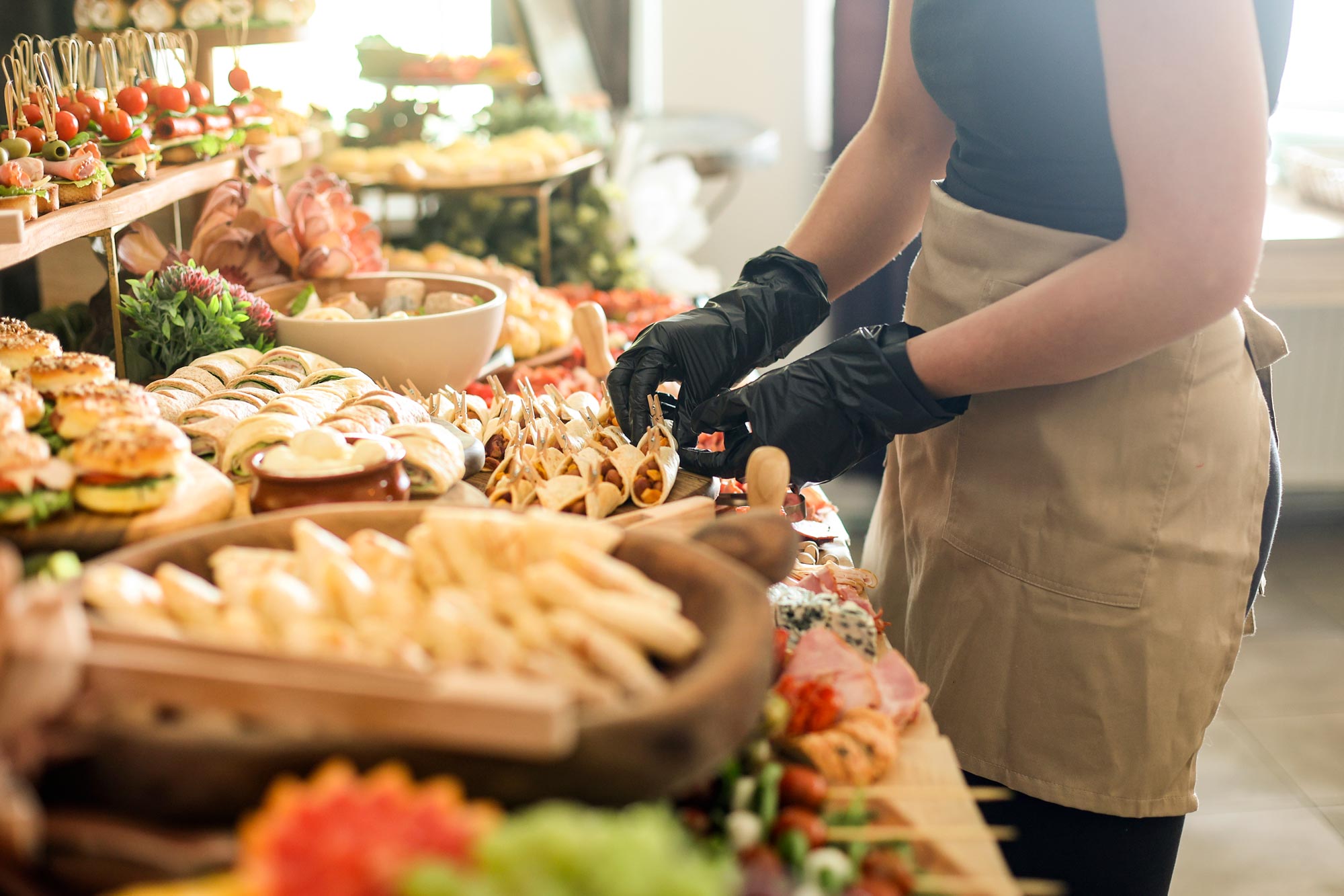 Person med förkläde arrangerar snittar vid ett luxuöst buffébord